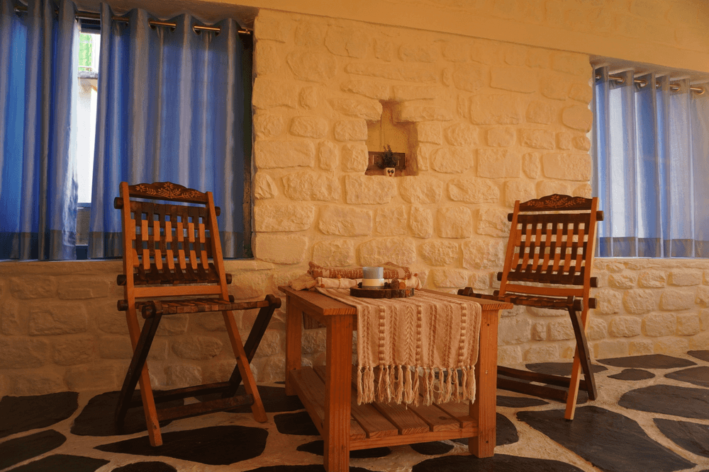 Two wooden armchairs and a tea table under the window