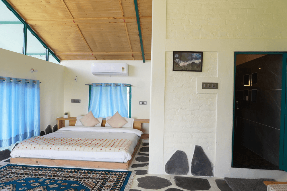 Bed with blue curtains and the bathroom door