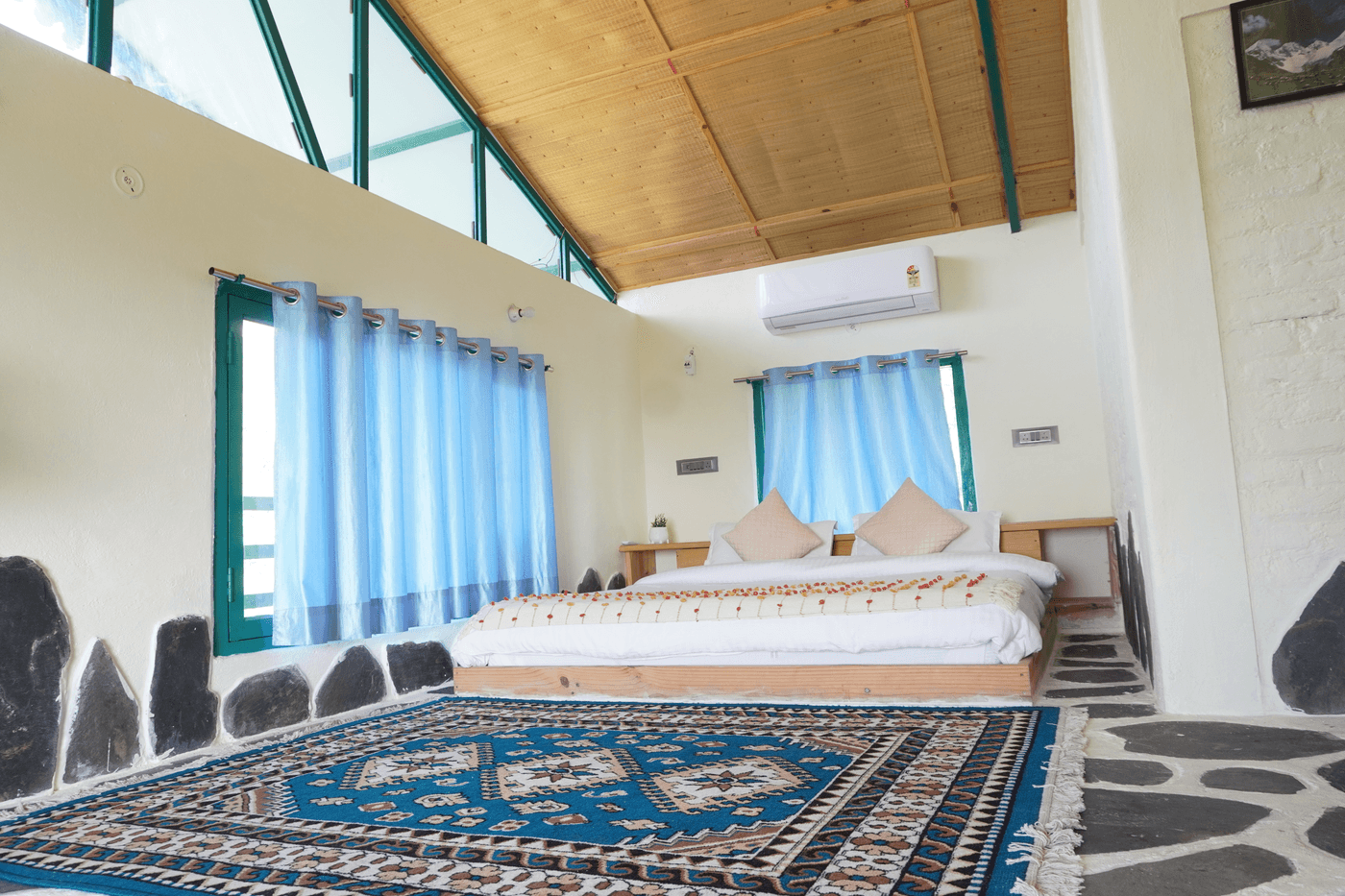 Sunset View Room: double bed, patterned rug and AC under a wooden ceiling