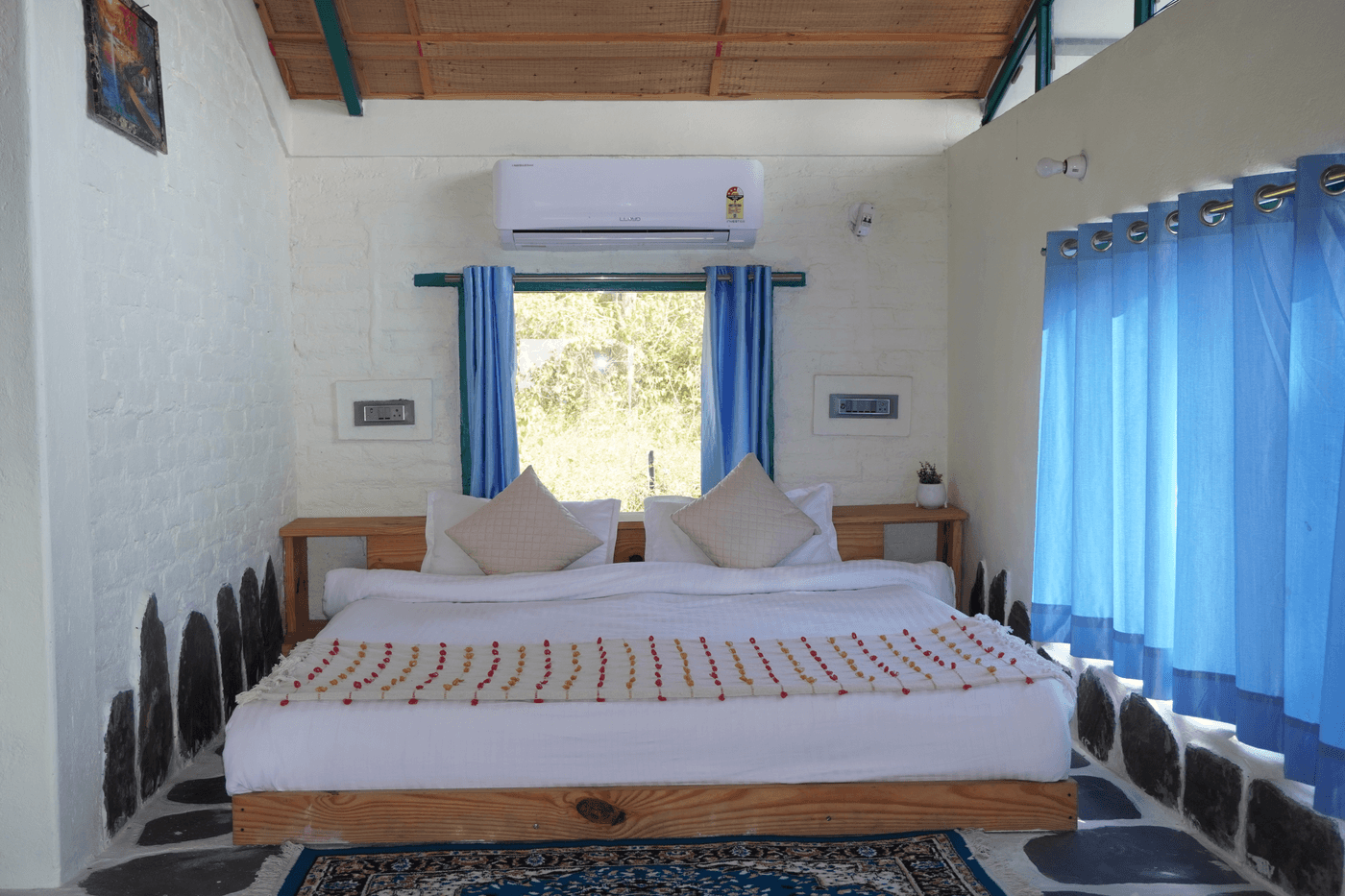 Dusk View Room: double bed under a wooden ceiling with AC and blue curtains